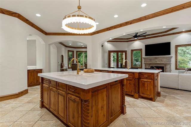 kitchen featuring sink, decorative light fixtures, plenty of natural light, and an island with sink