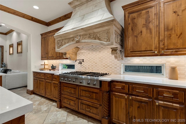 kitchen with tasteful backsplash, crown molding, custom exhaust hood, and stainless steel gas stovetop