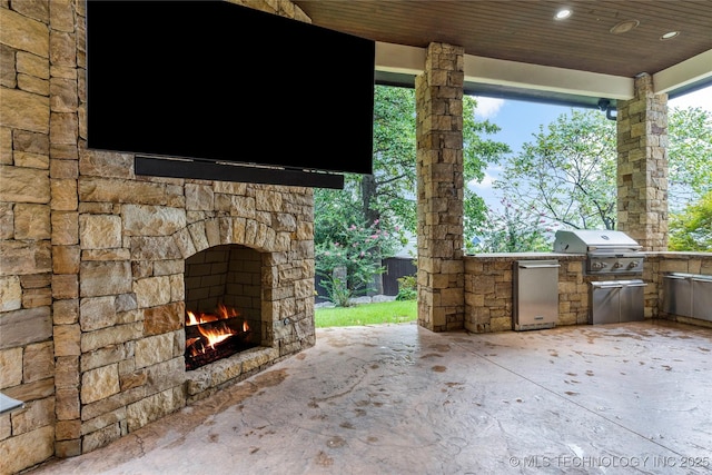 view of patio / terrace featuring area for grilling and an outdoor stone fireplace