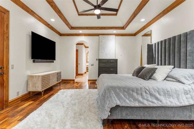 bedroom featuring ornamental molding, a tray ceiling, ceiling fan, and dark wood-type flooring