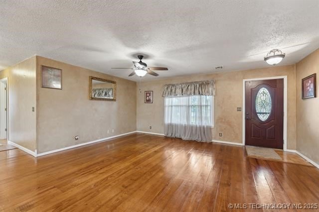 foyer with hardwood / wood-style flooring, a textured ceiling, and ceiling fan