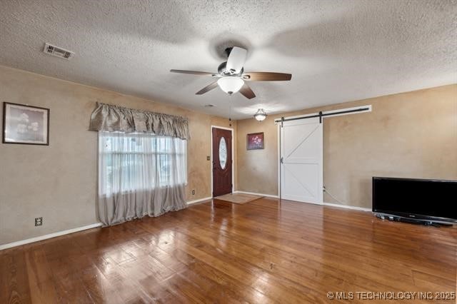 foyer featuring hardwood / wood-style flooring, a textured ceiling, ceiling fan, and a barn door