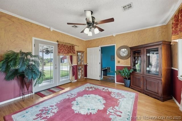 sitting room featuring crown molding, hardwood / wood-style flooring, a textured ceiling, and ceiling fan