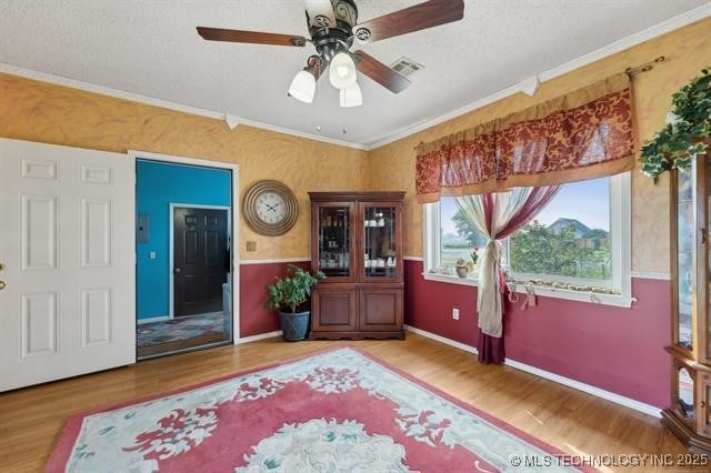 entrance foyer with ceiling fan, crown molding, a textured ceiling, and wood-type flooring