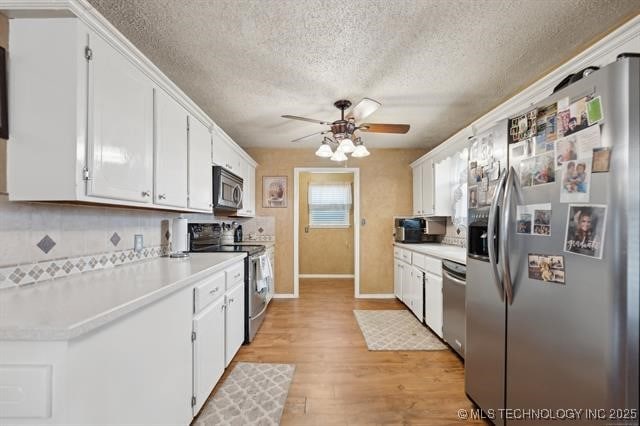 kitchen with light hardwood / wood-style floors, white cabinetry, decorative backsplash, and stainless steel appliances