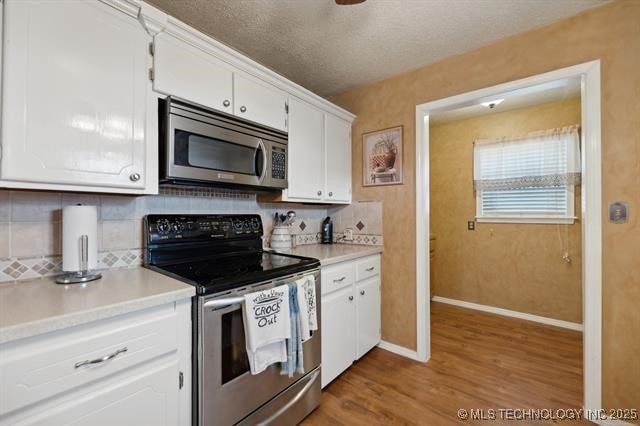 kitchen with backsplash, white cabinetry, and stainless steel appliances