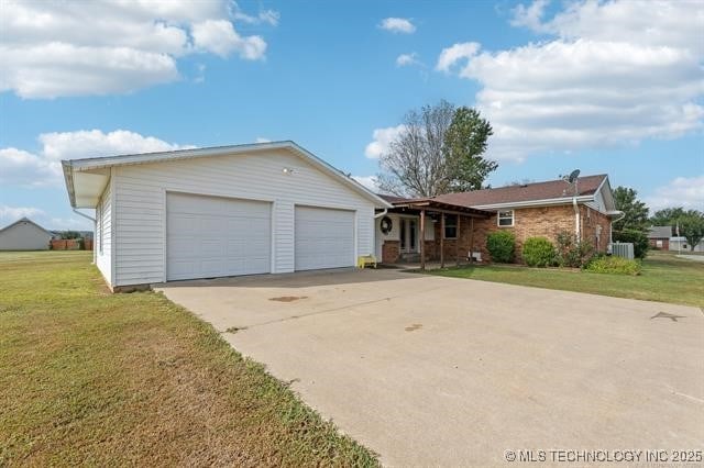 ranch-style home featuring a garage, central AC, and a front yard