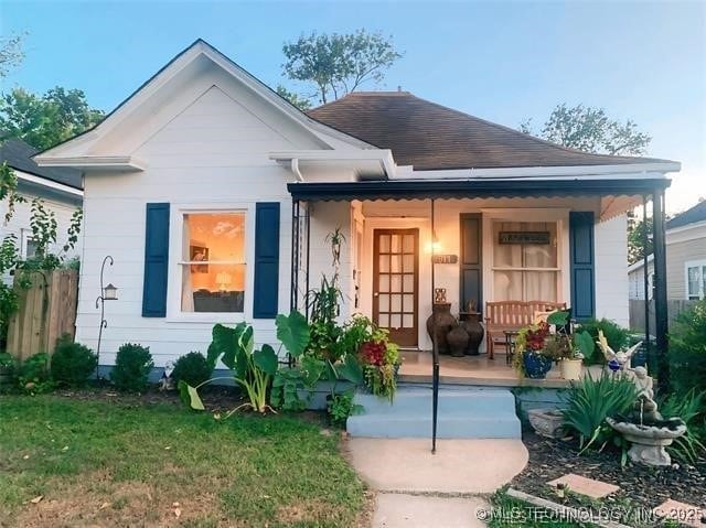 bungalow-style home featuring covered porch and a front yard