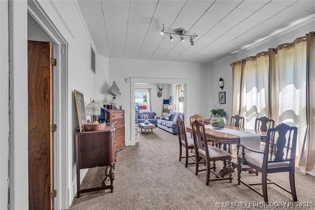 carpeted dining space featuring wooden ceiling