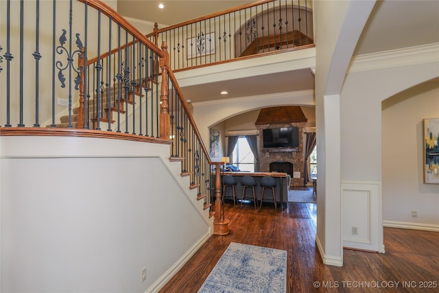 stairway featuring hardwood / wood-style flooring, ornamental molding, and a fireplace