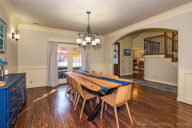 dining area featuring french doors, ornamental molding, dark wood-type flooring, and an inviting chandelier