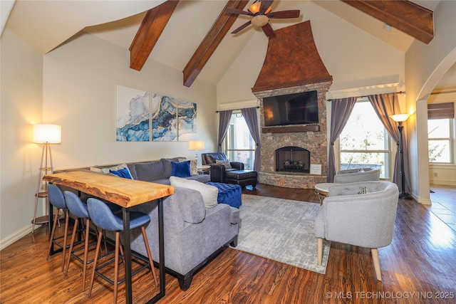 living room featuring hardwood / wood-style flooring, ceiling fan, a fireplace, and beamed ceiling