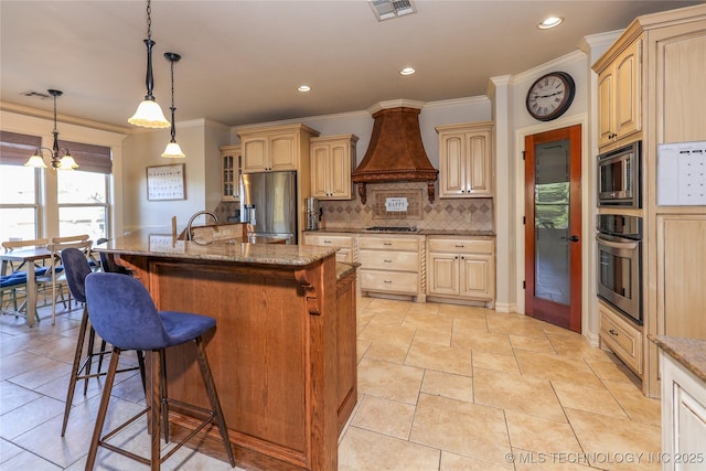 kitchen featuring custom exhaust hood, an island with sink, a notable chandelier, light stone counters, and stainless steel appliances