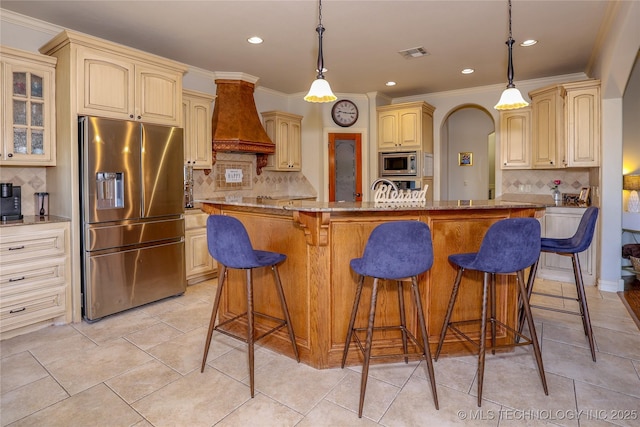 kitchen featuring backsplash, custom range hood, a kitchen island with sink, and appliances with stainless steel finishes