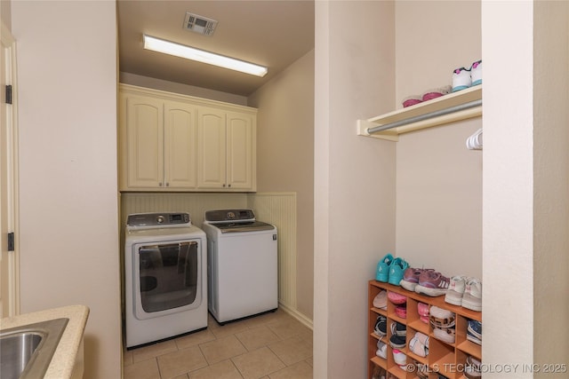 laundry room with washer and clothes dryer, light tile patterned floors, cabinets, and sink