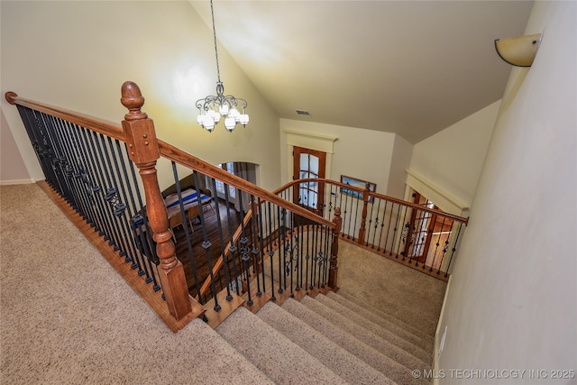 staircase featuring a notable chandelier, carpet floors, and vaulted ceiling