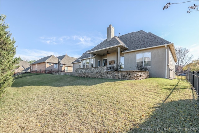 rear view of property with ceiling fan and a lawn