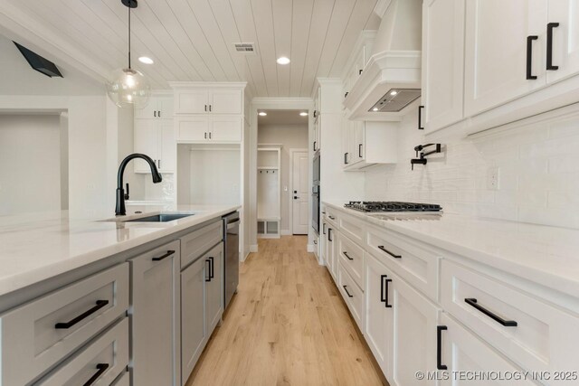 1303 Oakhurst Cir, Claremore, OK 74017 - kitchen with a sink, custom range hood, stainless steel appliances, wooden ceiling, and light wood-type flooring