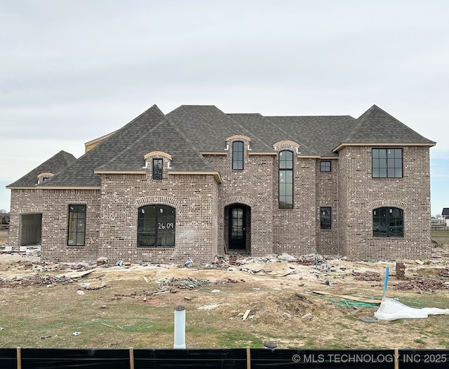 french country home with brick siding and roof with shingles