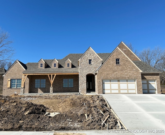 view of front of home with an attached garage, brick siding, a shingled roof, driveway, and stone siding