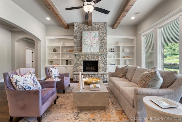 2787 Forest View Dr, Claremore, OK 74017 - living room featuring arched walkways, ceiling fan, baseboards, built in features, and a stone fireplace