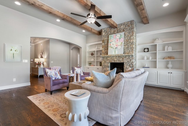 2787 Forest View Dr, Claremore, OK 74017 - living room featuring arched walkways, baseboards, dark wood finished floors, ceiling fan, and a stone fireplace
