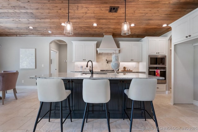 2787 Forest View Dr, Claremore, OK 74017 - kitchen featuring wall oven, custom exhaust hood, stainless steel microwave, wood ceiling, and white cabinets