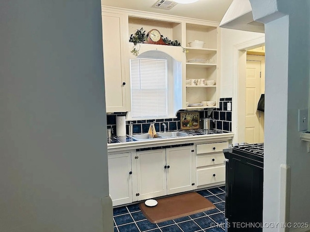 kitchen featuring white cabinetry, tile counters, dark tile patterned floors, backsplash, and refrigerator