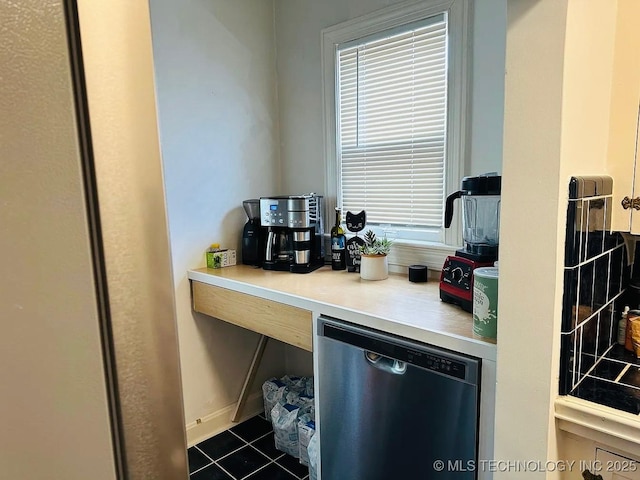 kitchen with stainless steel dishwasher and dark tile patterned flooring