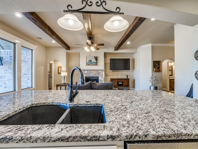 kitchen with pendant lighting, light stone countertops, sink, and beamed ceiling