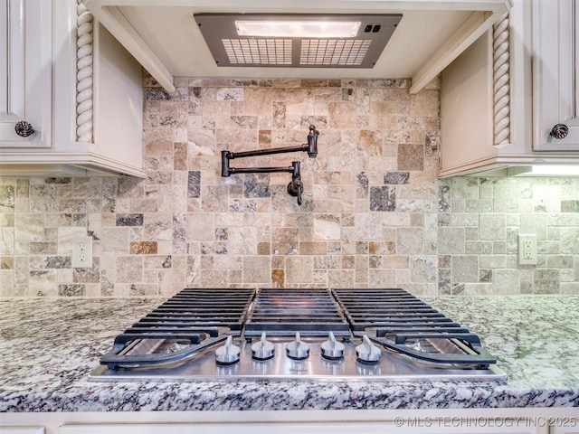 kitchen with tasteful backsplash, light stone counters, and stainless steel gas cooktop