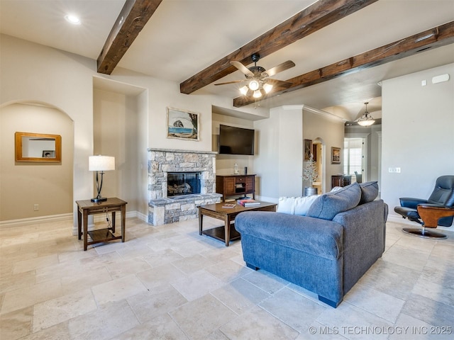 living room featuring ceiling fan, beam ceiling, and a fireplace