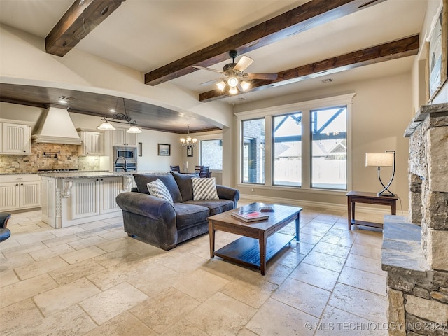 living room featuring beamed ceiling, ceiling fan with notable chandelier, and sink