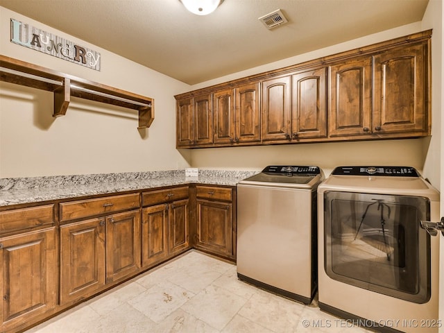 clothes washing area with washer and clothes dryer and cabinets