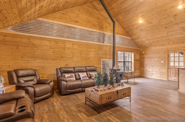 living room with wood ceiling, wooden walls, wood-type flooring, high vaulted ceiling, and a wood stove