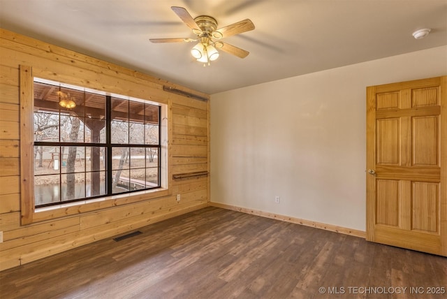 unfurnished room featuring wood walls, ceiling fan, and dark hardwood / wood-style floors