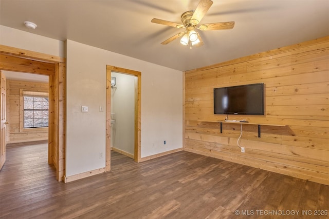 unfurnished living room with ceiling fan, dark wood-type flooring, and wooden walls