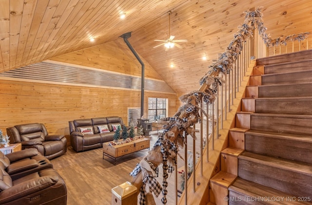 living room with a wood stove, ceiling fan, wooden ceiling, wood walls, and hardwood / wood-style flooring