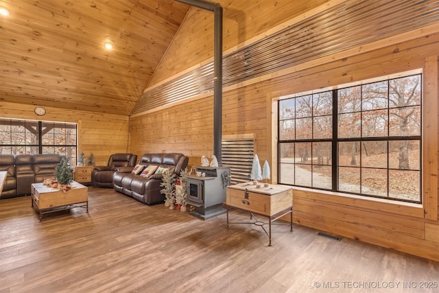 living room featuring a wood stove, a healthy amount of sunlight, high vaulted ceiling, and wooden ceiling