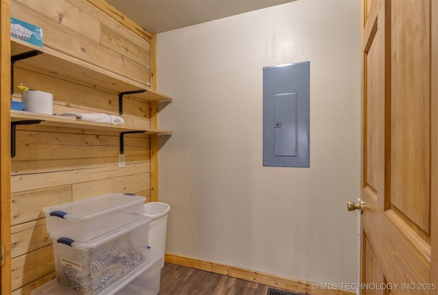 interior space featuring electric panel, wooden walls, and dark hardwood / wood-style flooring