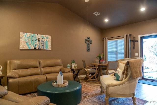 living room featuring a healthy amount of sunlight, wood-type flooring, and vaulted ceiling