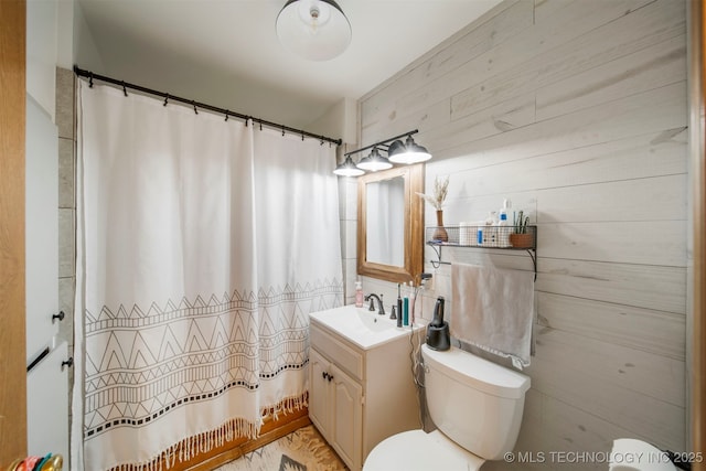 bathroom featuring vanity, toilet, and wooden walls