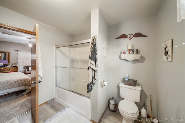 bathroom featuring hardwood / wood-style floors, enclosed tub / shower combo, and toilet