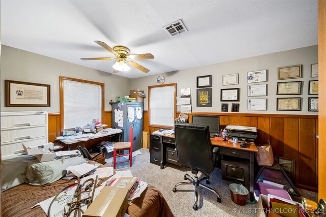 office area with ceiling fan, wood walls, and light colored carpet