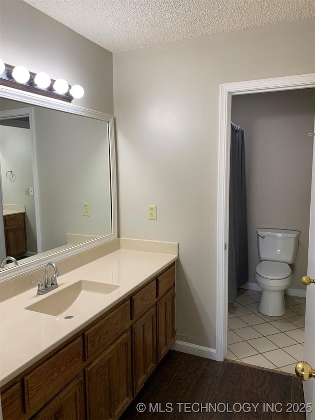 bathroom featuring vanity, tile patterned floors, a textured ceiling, and toilet