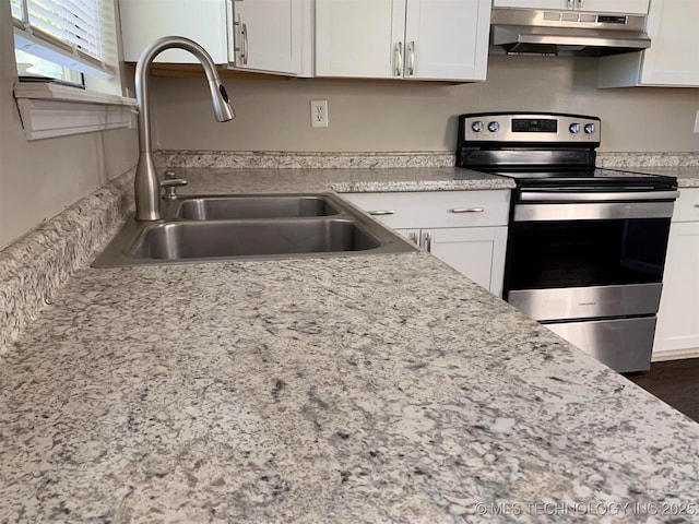 kitchen featuring stainless steel electric stove, white cabinetry, sink, and light stone counters