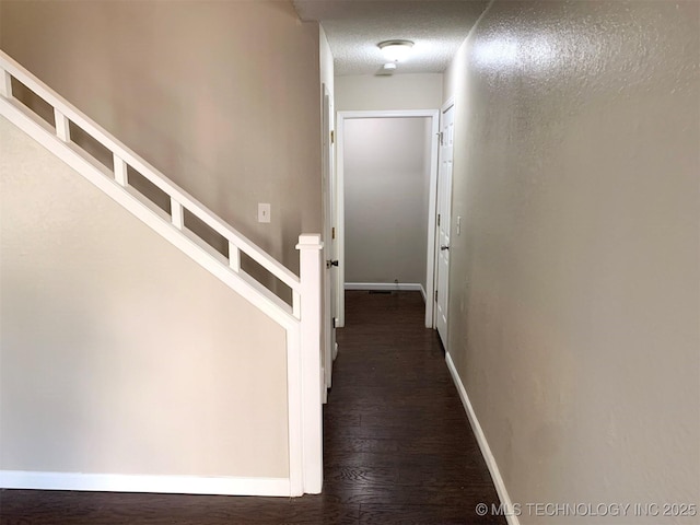 corridor with dark hardwood / wood-style floors and a textured ceiling