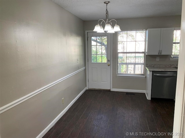 doorway featuring a textured ceiling, dark wood-type flooring, and a notable chandelier