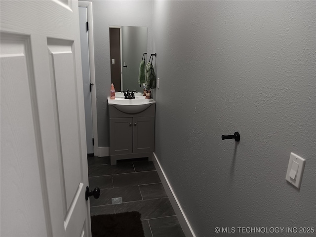 bathroom with a textured wall, tile patterned flooring, baseboards, and vanity