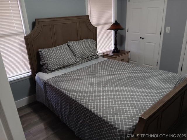 bedroom featuring a closet, dark wood finished floors, and baseboards